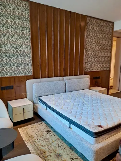 The fully assembled custom bed against a feature wall of wood and wallpaper. The neutral upholstery of the bed provides a calm counterpoint to the rich textures of the wall.