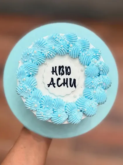 A simple blue birthday cake with piped buttercream flowers and pearl sprinkles.