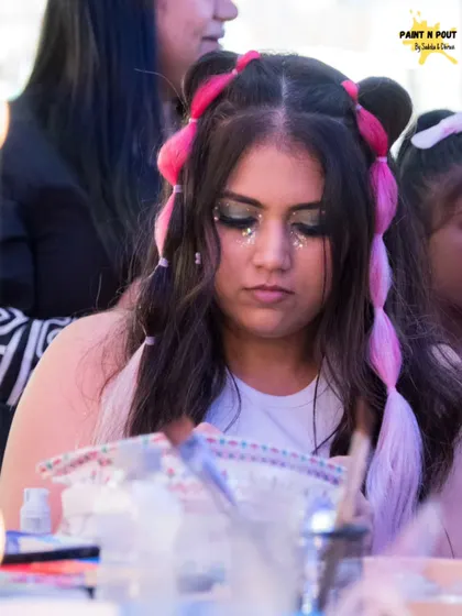 A client with a dramatic silver glitter eye look and fun pink hair extensions, getting ready for a fun event.
