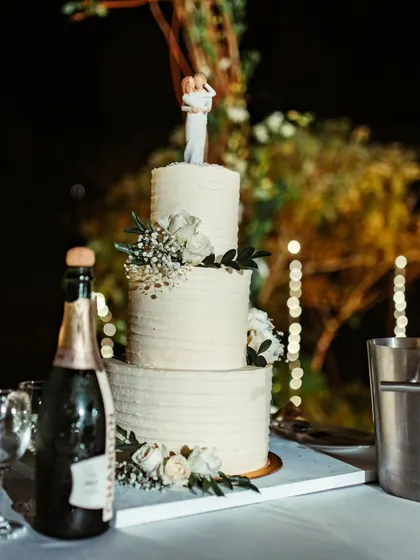 A beautiful three-tiered wedding cake with a custom topper, ready for the couple to cut and celebrate their union.