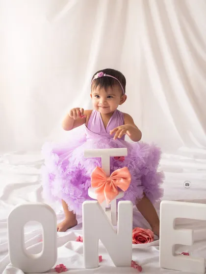 Ready to ride into year two. A happy birthday girl with her tricycle and "ONE" letters.