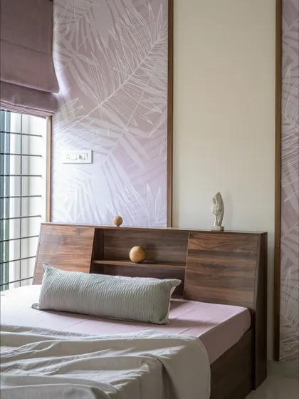 This bedroom for the grandfather features a walnut headboard with built-in storage and soft lavender wallpaper panels. The design is calm, grounded, and timeless.