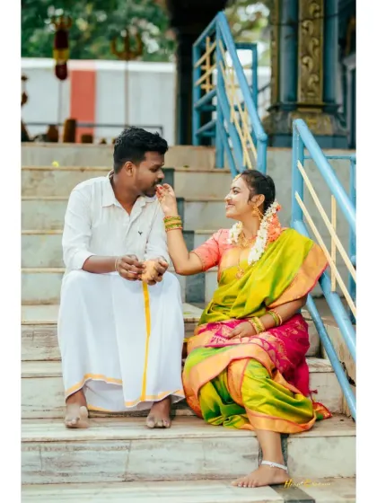 A playful and sweet moment on temple steps, as the bride-to-be lovingly touches the groom's cheek. Their traditional outfits add to the charm.