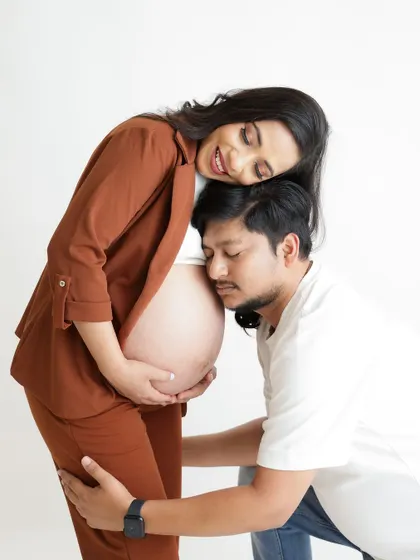Listening for the first hello. This classic pose captures the dad-to-be's ear to the baby bump, a timeless expression of love and anticipation.