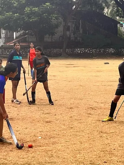 Our girls team practicing on a dirt field. This image shows our dedication to the game, proving that our passion for hockey thrives in any environment, turf or not.