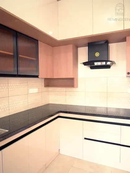 A bright and modern L-shaped kitchen with off-white and light wood cabinets. This project for a 3BHK apartment at Prestige Finsbury Park was designed to be sophisticated yet warm and inviting.