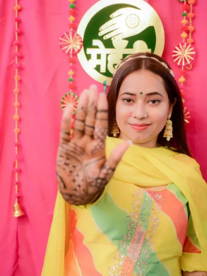 The bride proudly displays her palm, stained with our natural henna, against the festive backdrop of her mehandi ceremony.