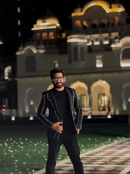 The hustle begins. A classic black suit against a palace-like backdrop, setting the stage for a night of grand celebrations and entertainment.