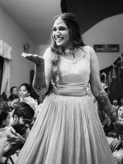 Fun and candid moments from a mehendi ceremony. The bride's makeup is fresh and playful, with a winged liner and glowing skin, perfect for celebrating with her loved ones. The hairstyle is a soft half-updo with pretty accessories.