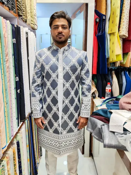 A modern take on the sherwani. This open-style jacket features a grey and white geometric pattern, layered over a sequined kurta and pant for a stylish, contemporary look.