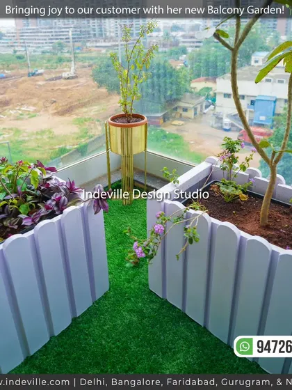 A close-up of the custom white picket-style planters. The mix of flowering plants and the golden planter stand add layers of color and texture to the balcony garden.