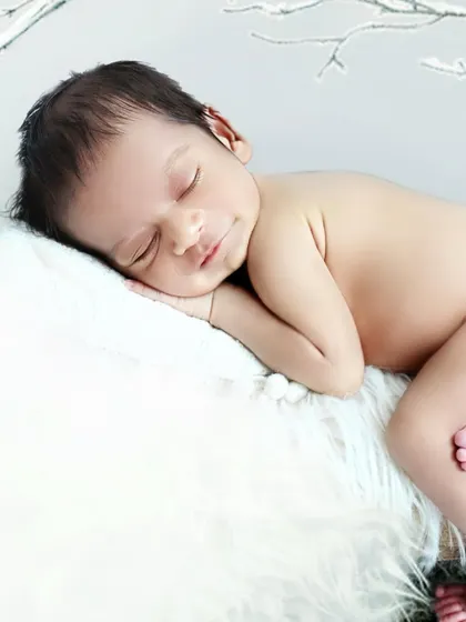 A simple and serene close up portrait of a sleeping newborn, resting peacefully on a soft white fur blanket. This pose highlights their delicate features and peaceful expression.