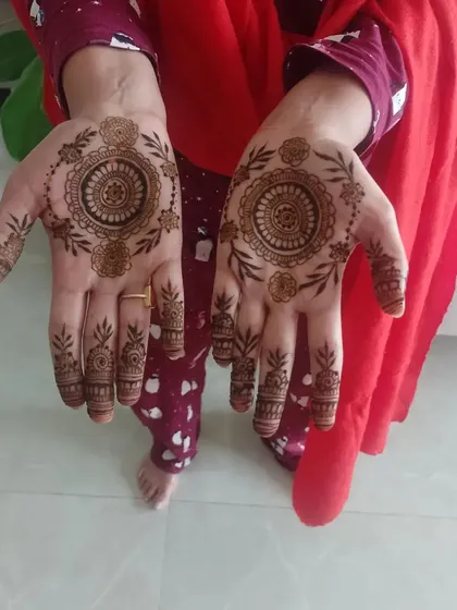 A delicate mandala design with leafy vines extending towards the fingers, a lovely choice for any party.