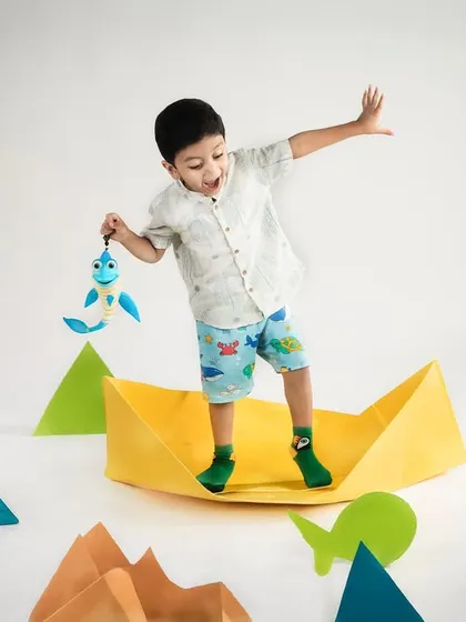 Gone fishing in a sea of imagination! A little boy stands in a paper boat, "fishing" for paper fish in this fun and creative studio setup.