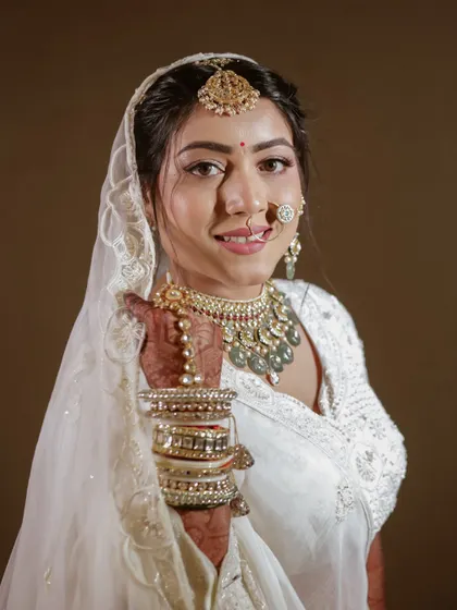 A confident and happy portrait of the bride, showcasing her beautiful smile and traditional wedding jewelry.