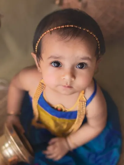 A striking top-down portrait of a baby girl from the mango-themed shoot. Her expressive eyes and the traditional styling create a captivating and artistic image.