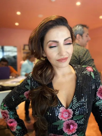 A close-up of the messy side braid, showing the texture and volume. The pink eyeshadow complements the floral details on her outfit.