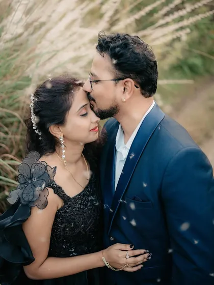 A gentle forehead kiss amidst tall grass. The soft focus and natural elements add to the romantic feel of this portrait.