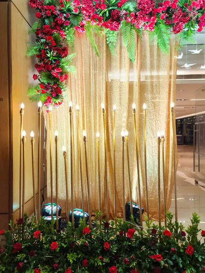 A detail shot of our candle wall setup. The warm glow of the bulb-topped golden rods against a shimmering gold curtain creates a rich and inviting atmosphere.
