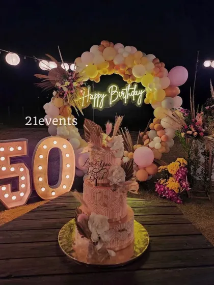 I also design elegant outdoor setups for milestone birthdays. This 50th birthday celebration featured a rustic boho theme with a balloon arch in warm tones, a 'Happy Birthday' neon sign, and large marquee numbers, creating a magical evening ambiance.