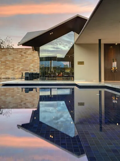 The Lotus Cafe at the Dasavatara Hotel in Tirupati, where the modern, angular roof reflects on the water at dusk, creating a dialogue between the structure and its environment.