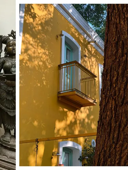 A sunny yellow wall with a charming balcony, the shadows of a tree creating a beautiful pattern across the facade.