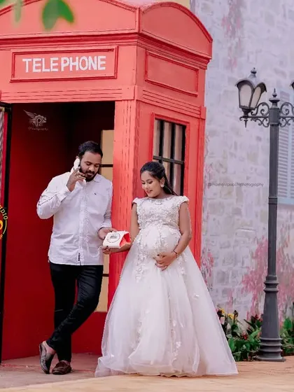 A fun, themed maternity shoot with a classic red telephone booth. The white gown offers a lovely contrast and adds to the romantic, vintage feel of the photo.
