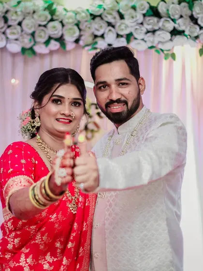 A fun and happy shot of an engaged couple showing their rings to the camera with a thumbs-up gesture.