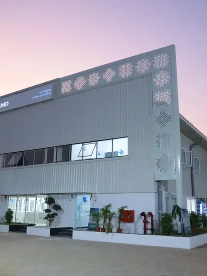 A dusk view of the factory facade, where architectural lighting highlights the building's form and decorative elements. The design ensures the facility maintains a strong presence at all hours.