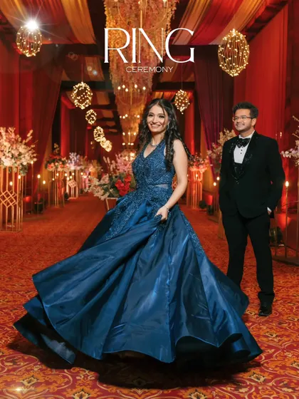 A grand and cinematic shot of the couple at their ring ceremony. The bride's flowing blue gown and the opulent decor create a fairytale-like atmosphere.