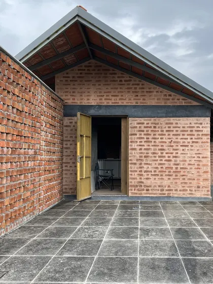 A view of the brick jali wall and a side entrance at the NallaNela farmhouse. The perforated brickwork allows for ventilation while maintaining privacy.