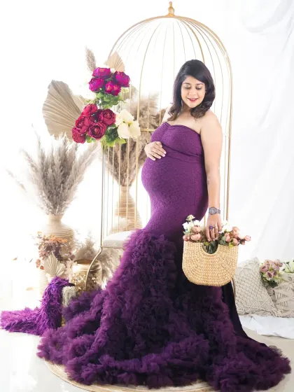 A beautiful solo portrait celebrating motherhood. The mom-to-be is wearing a stunning purple gown, seated in our golden birdcage chair for an elegant look.