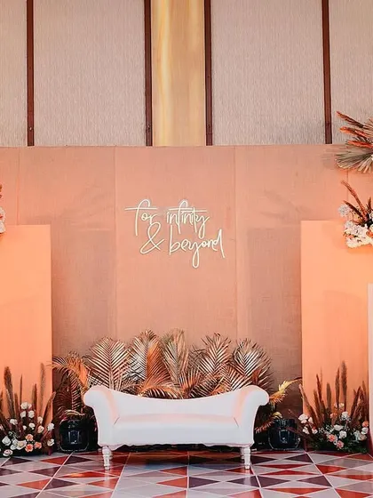 The engagement stage in full view. We used a warm, peachy color palette, dried palm leaves, and modern arched panels to create a backdrop that was chic, romantic, and perfectly on-trend.