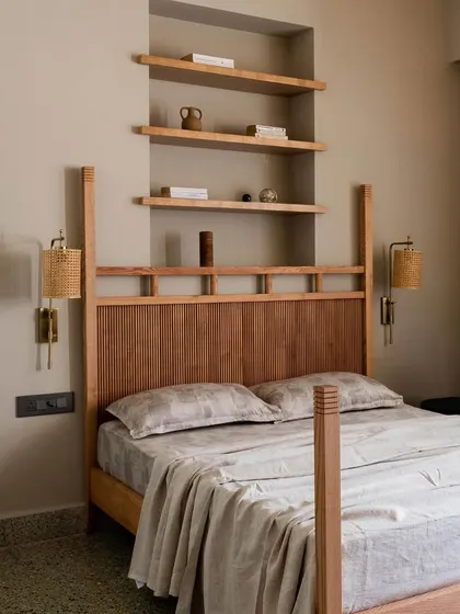 A bedroom in Apartment 5026, featuring a custom four-poster bed and open shelving. The combination of the warm wood, patterned curtains, and original terrazzo floor creates a space that is both nostalgic and timeless.