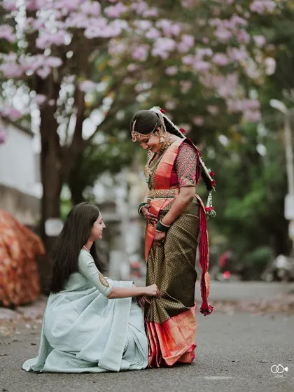 A sweet moment between the bride and her bridesmaid, who is helping her with her saree.