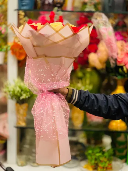 A tall bouquet of red and yellow roses wrapped in shimmering pink paper. This shows how the wrapping style can add height and drama to an arrangement.