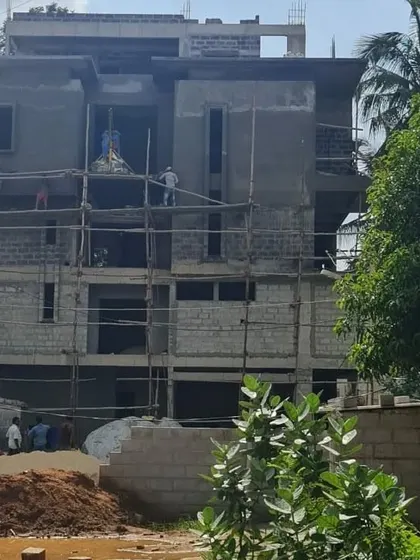 A villa project during the construction phase. The scaffolding is up, and the basic form of the building is complete, with plastering work underway.