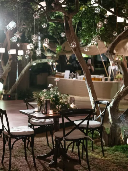 An intimate seating arrangement under trees adorned with hanging glass orbs and lanterns. We create cozy nooks for guests to relax and converse.