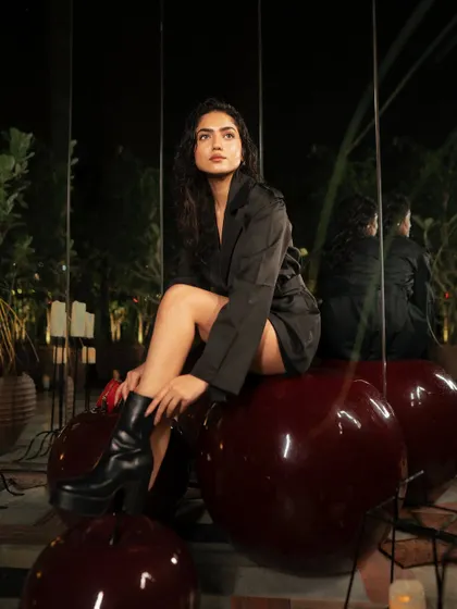 A creative on-location shot using large, reflective cherry sculptures as a prop. The reflections and the unique setting make for a memorable and artistic fashion image.