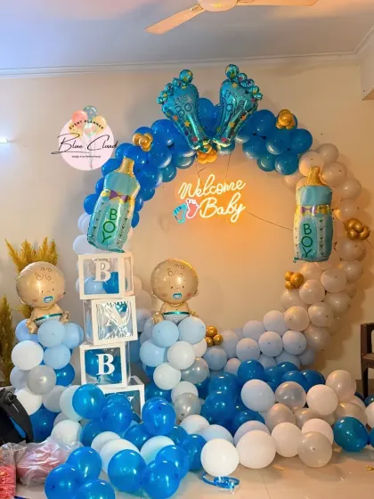 A 'Welcome Baby' boy setup with a blue and white balloon ring, neon sign, and 'BABY' blocks.
