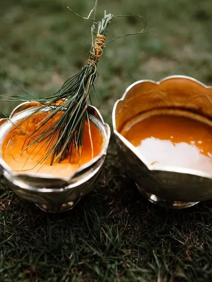 A close-up of the Haldi paste in traditional silver bowls. We capture the details and textures that make up the story of your wedding.