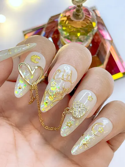 An elegant Eid Mubarak nail art design in white and gold, featuring crescent moons, stars, and delicate 3D gold lettering.