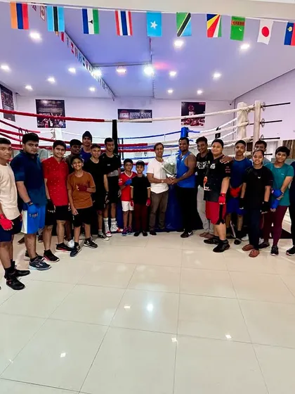 A full group photo celebrating our founder's achievement. We are more than an academy; we are a family that supports each other's success inside and outside the ring.
