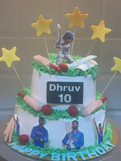 A two-tier cricket lover's cake, perfect for a young fan. It features edible photos of Indian cricket players, fondant bats and balls, and a player topper.