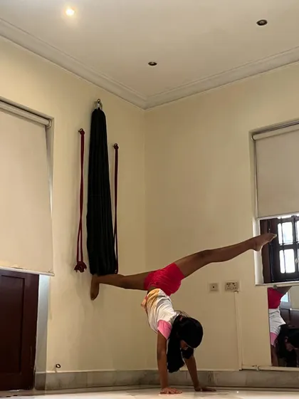 A duplicate of image 11, showing a young student's impressive wall-assisted split handstand.