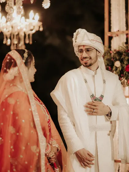 The groom’s loving gaze as he sees his bride during the ceremony. This candid shot captures his genuine smile and the happiness of the moment, with the elegant decor softly blurred in the background.