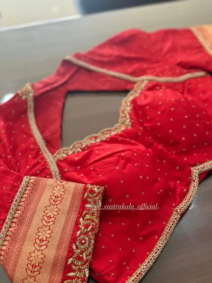 A red blouse with a brocade sleeve cuff, combining two different textures and patterns.