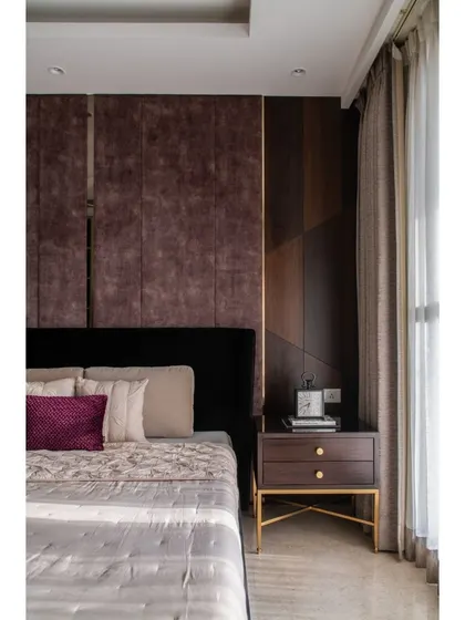 A detail shot of the bedside area, showing how the warm walnut paneling and the sleek lines of our custom nightstand complement the dramatic black bed. The brass legs on the table add a touch of warmth.