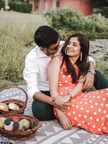 A sweet and romantic moment during a picnic-themed pre-wedding shoot. The natural green setting and their loving gaze create a perfect picture of contentment.
