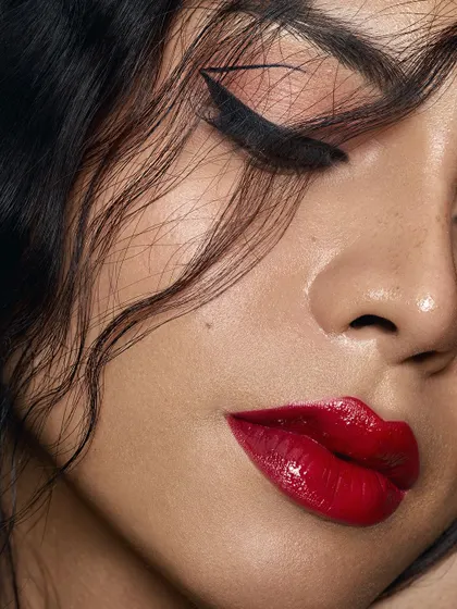 A close-up detail shot focusing on the texture of the glossy red lips and the sharp, black winged liner. This macro perspective highlights the MUA's artistry and our ability to capture fine details with precision.